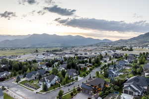 Aerial view of property and surrounding area featuring nearby suburban area and a mountainous background