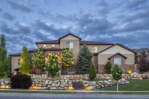 View of front facade with stone siding and a front lawn