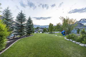 View of grassy yard with a mountain view and a playground