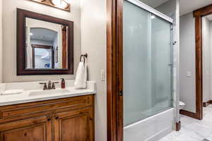 Bathroom with vanity and combined bath / shower with glass door