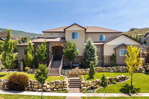 View of front of home with stone siding, a front yard, a mountain view, and stairs