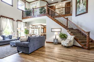Living room with ornamental molding, a towering ceiling, wood finished floors, stairway, and arched walkways