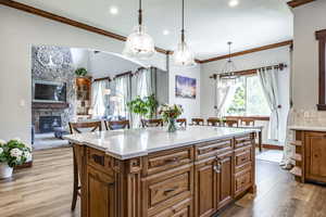 Kitchen featuring a breakfast bar, light wood-style flooring, brown cabinets, recessed lighting, and light countertops