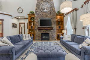 Living room with a fireplace, a high ceiling, wood finished floors, crown molding, and arched walkways