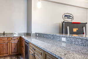 Kitchen featuring brown cabinets, light stone counters, and wood finished floors