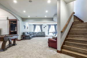 Carpeted living area featuring arched walkways, recessed lighting, and stairway