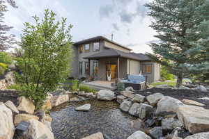 Back of property with a garden pond, a hot tub, and stucco siding