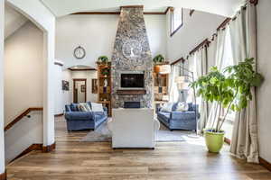 Living room featuring arched walkways, a fireplace, a high ceiling, and wood finished floors