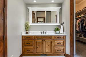 Bathroom featuring vanity, a walk in closet, and recessed lighting