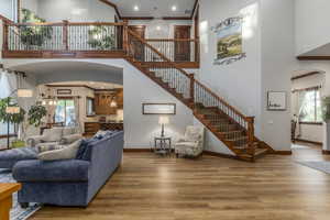 Living area featuring a high ceiling, arched walkways, stairs, wood finished floors, and crown molding