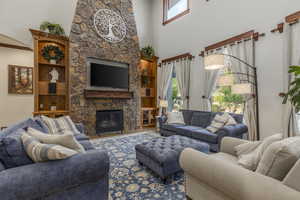 Living area featuring a high ceiling and a stone fireplace
