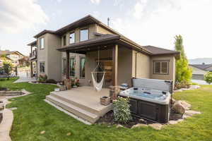 Back of house featuring a hot tub, stucco siding, and a wooden deck