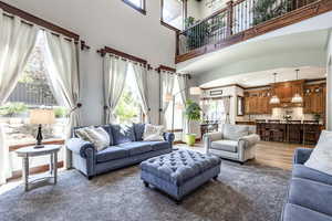 Living area with healthy amount of natural light, wood finished floors, and a towering ceiling