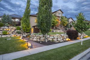 View of property hidden behind natural elements with stairs, a front yard, and a deck