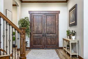 Foyer featuring stairway, dark wood-type flooring, ornamental molding, and arched walkways