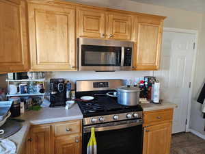 Kitchen with appliances with stainless steel finishes, light countertops, and tile patterned flooring