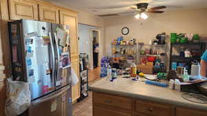 Kitchen featuring light tile patterned flooring, ceiling fan, water heater, light countertops, and light brown cabinetry