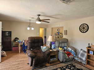 Living room featuring light wood-type flooring, a ceiling fan, and a textured ceiling