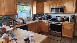 Kitchen with appliances with stainless steel finishes, light countertops, and tile patterned floors