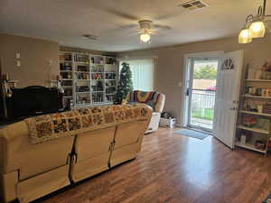 Living area featuring wood finished floors, ceiling fan, and a textured ceiling