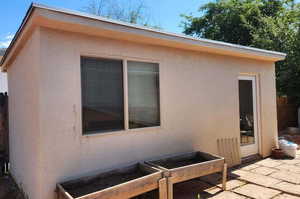 View of side of property featuring stucco siding and a vegetable garden