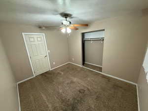 Unfurnished bedroom featuring a closet, carpet flooring, ceiling fan, and a textured ceiling
