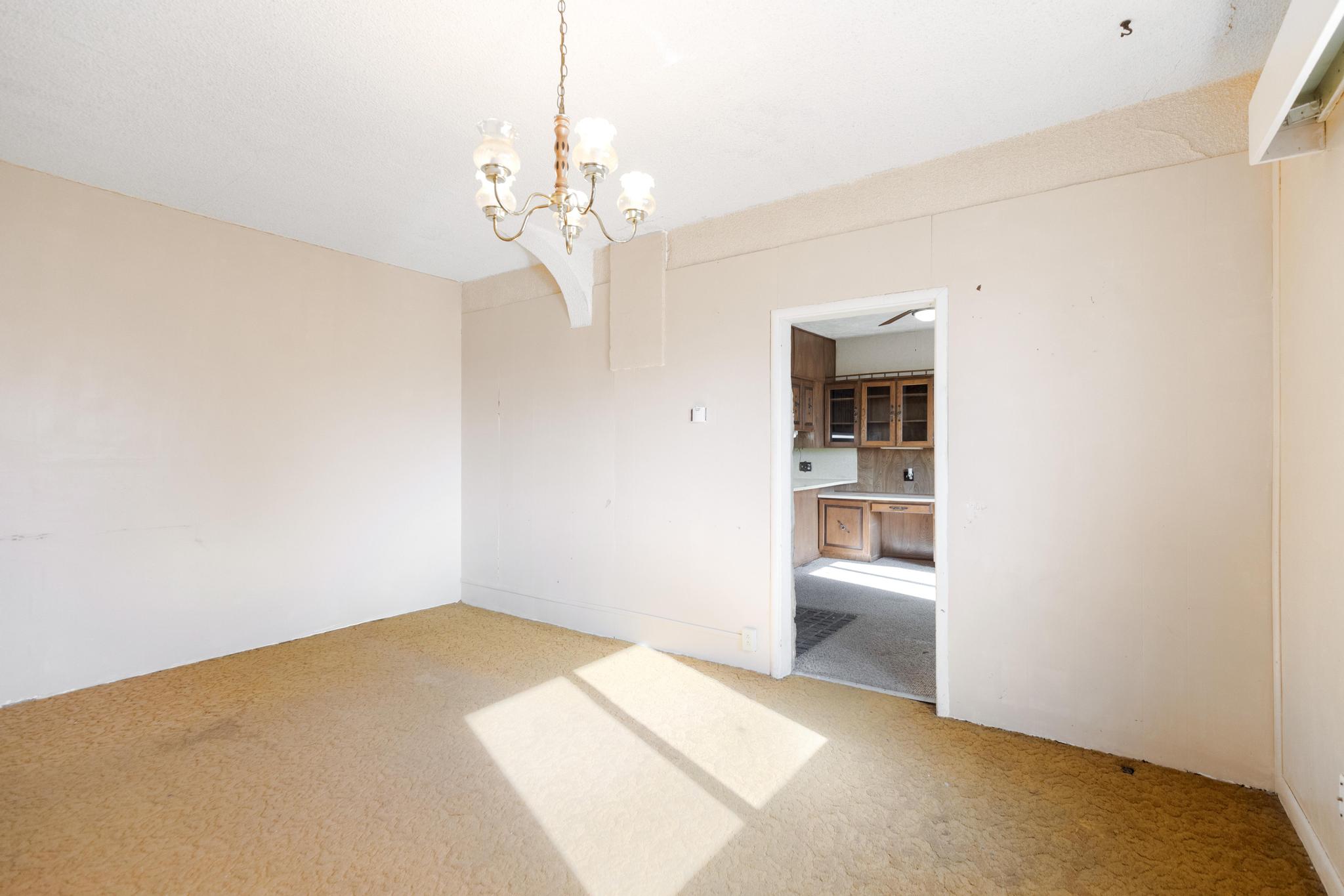 Spare room with an inviting chandelier and light carpet