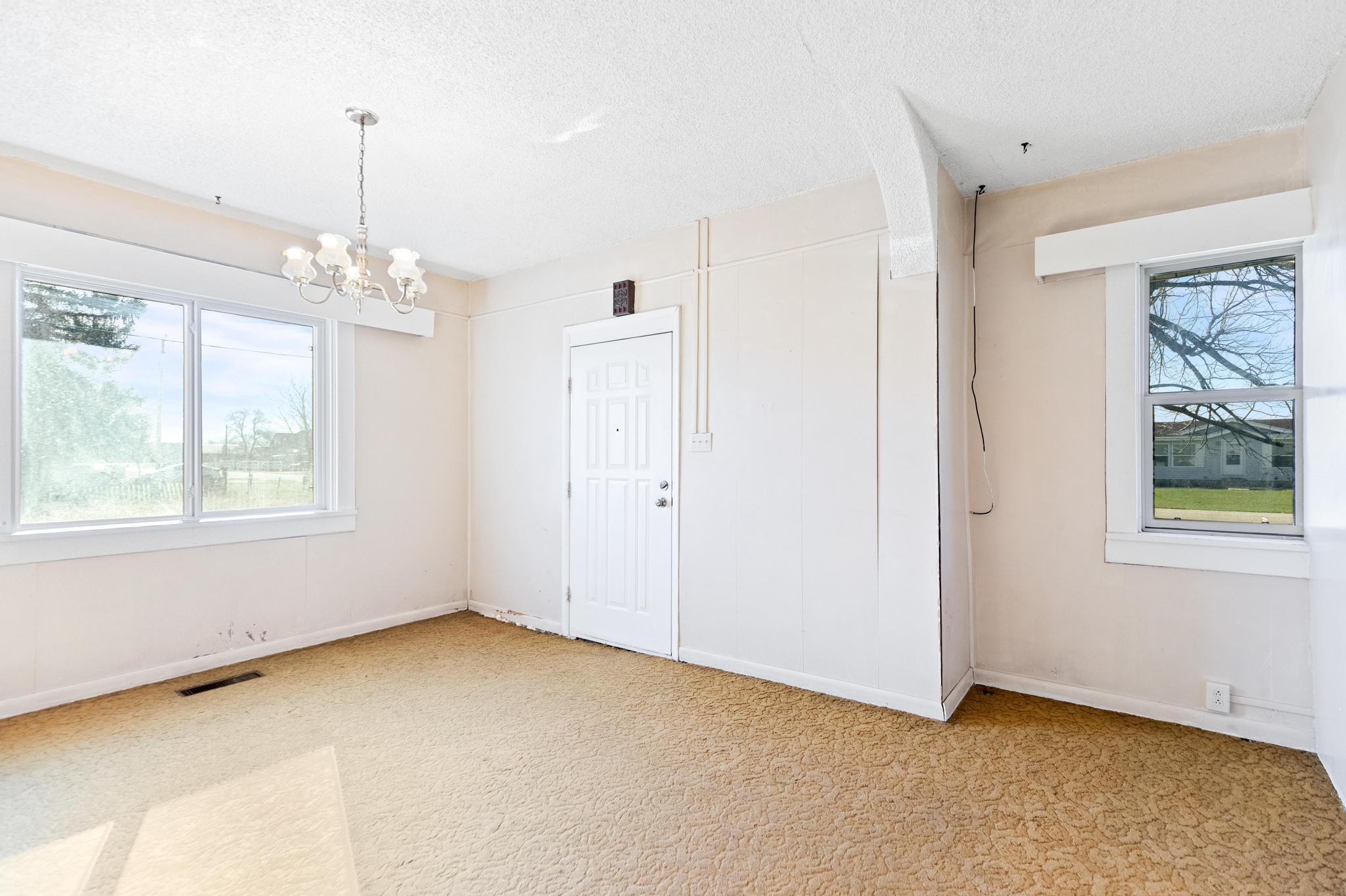 Empty room with a wealth of natural light, a notable chandelier, a textured ceiling, and visible vents