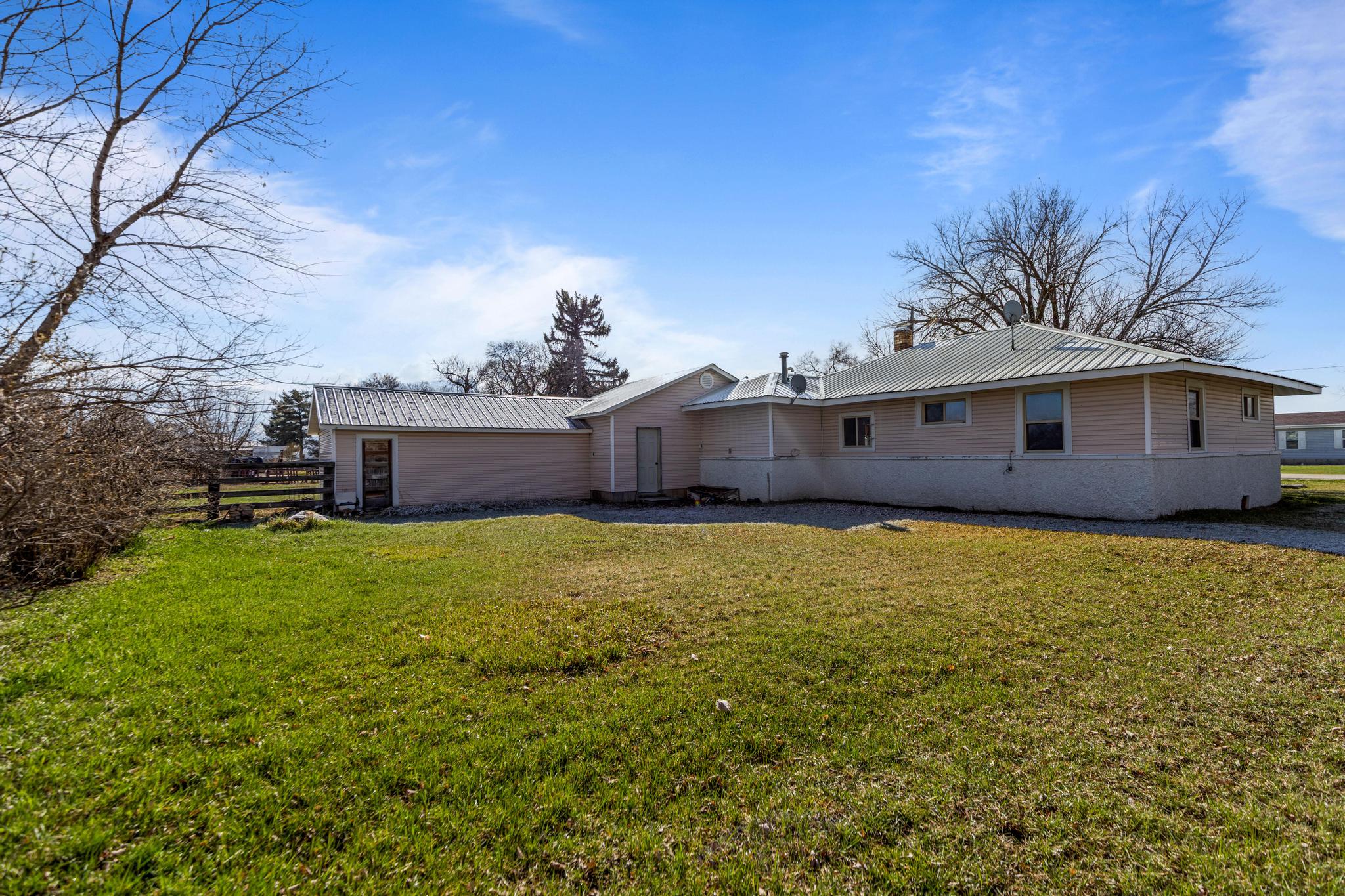 Back of property with a chimney, a lawn, and metal roof
