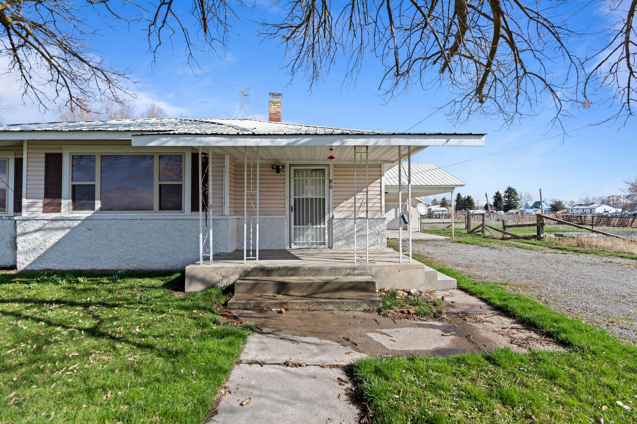 Bungalow-style home featuring a front lawn, fence, a chimney, and a porch