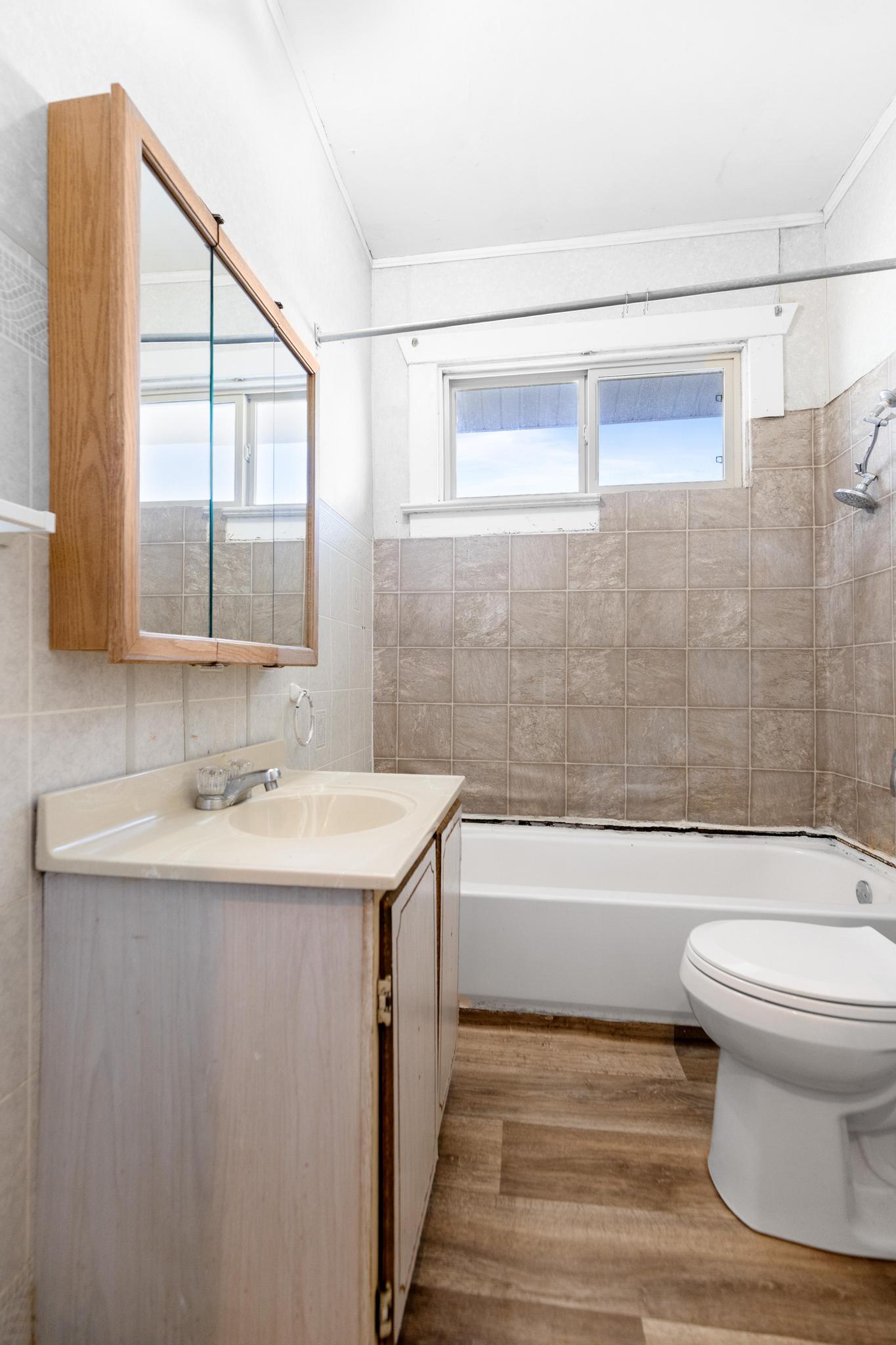 Bathroom with toilet, plenty of natural light, vanity, and wood finished floors