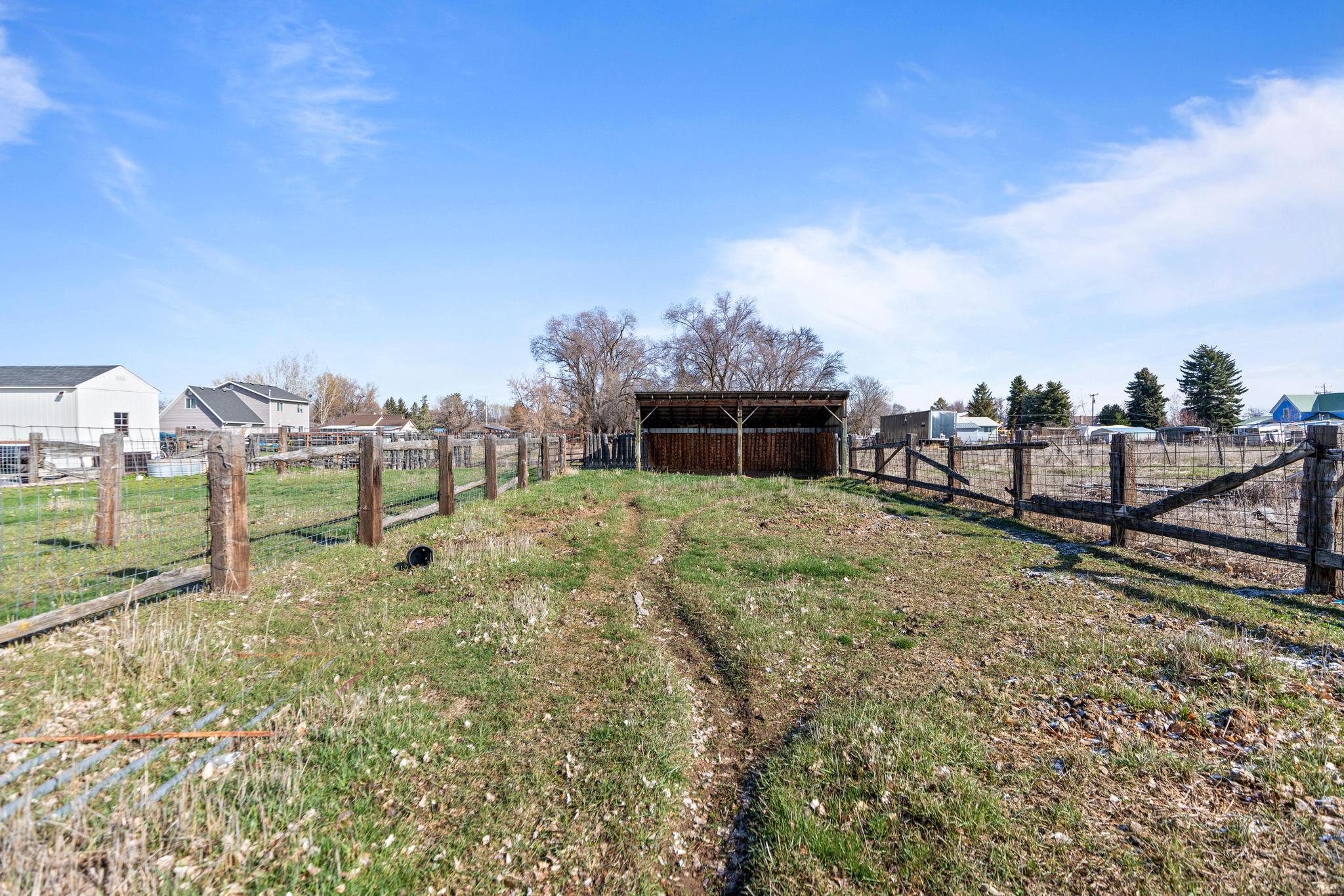 View of yard with an outbuilding, fence, a pole building, and a rural view