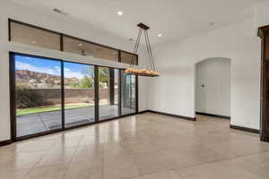 Tiled empty room with visible vents, baseboards, arched walkways, a notable chandelier, and recessed lighting
