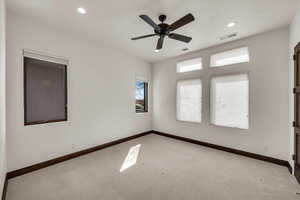 Empty room with carpet, visible vents, baseboards, and a ceiling fan