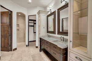 Bathroom with a sink, baseboards, double vanity, and tile patterned flooring