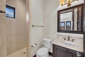 Bathroom with tasteful backsplash, tiled shower, vanity, and a healthy amount of sunlight