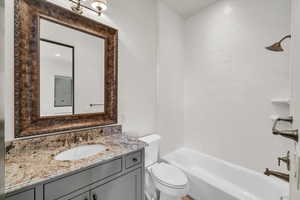 Bathroom featuring washtub / shower combination, toilet, and vanity
