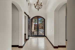 Entrance foyer with french doors, baseboards, arched walkways, and light tile patterned floors