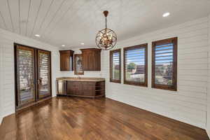 Interior space with dark wood-type flooring, wooden ceiling, dishwasher, french doors, and a notable chandelier