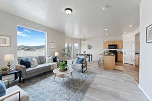 Living room with recessed lighting, light wood finished floors, a textured ceiling, and baseboards