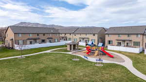 View of play area featuring a mountain view, fence, a residential view, and a lawn