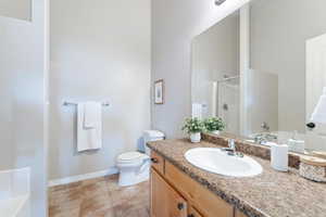 Full bathroom with baseboards, toilet, vanity, tile patterned floors, and a stall shower