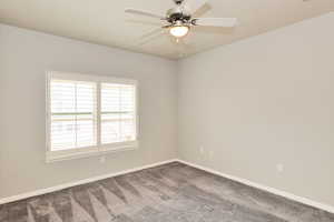 Carpeted spare room featuring baseboards and a ceiling fan