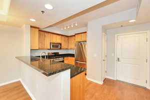 Kitchen featuring light wood-style flooring, a peninsula, baseboards, and stainless steel appliances