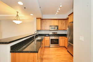 Kitchen with a sink, appliances with stainless steel finishes, a peninsula, recessed lighting, and light wood-style flooring