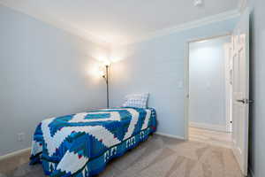 Bedroom featuring carpet, baseboards, and crown molding