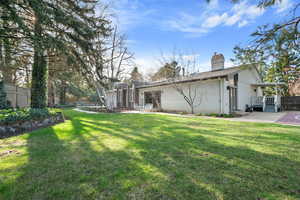 Rear view of property featuring a yard, a chimney, fence, and a patio area