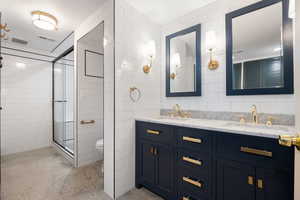 Full bath featuring a sink, visible vents, tile walls, and a stall shower