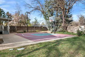 View of sport court featuring basketball court, a yard, and fence