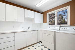 Washroom featuring separate washer and dryer, a sink, cabinet space, and light floors
